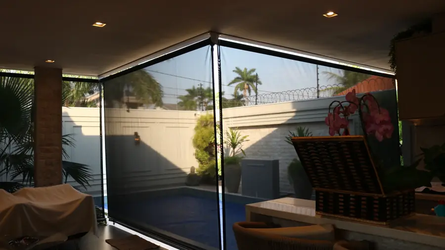 Área de lazer coberta com cortinas rolô e vista para a piscina