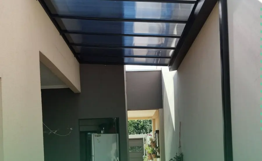 Corredor lateral coberto com policarbonato e estrutura metálica preta